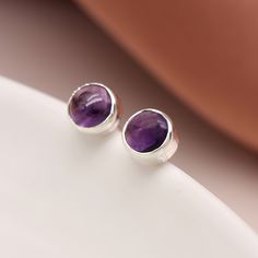 A pair of minimalistic sterling silver February birthstone stud earrings with natural purple amethyst gemstones make the perfect gift for wearers of all ages. Not to be found anywhere on the high street, our beautiful February birthstone studs are crafted from the finest sterling silver. Featuring gorgeous round purple Amethyst gemstones set in a beautiful silver setting, these dainty silver February birthstone earrings feature a classic butterfly and post fastening and are suitable for almost any age.  Our birthstone jewellery can be customised to match the recipient's birthstone or favourite colour or simply to represent their children or family members. Make your earrings even more special by choosing one of our beautiful card inserts, set inside the lid of a high-quality gift box. Add Everyday Purple Amethyst Earrings, Amethyst Studs, Birthstone Earrings, February Birthstone, Round Stud Earrings, Birthstone Earring, Amethyst Earrings, February Birth Stone, Amethyst Gemstone