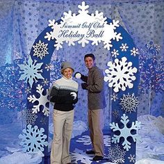 a man and woman standing in front of a blue backdrop with snowflakes on it