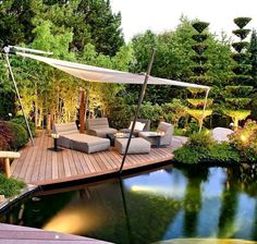 an outdoor deck with chairs and umbrellas next to a pond