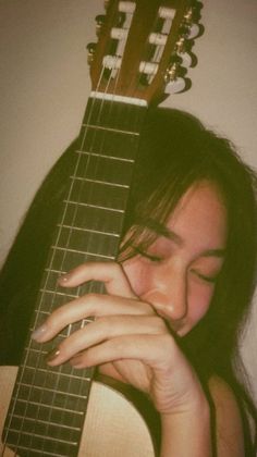 a woman holding an acoustic guitar up to her face