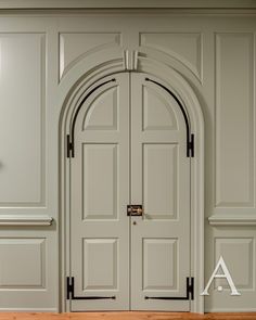 an arched door with wooden floors and white walls