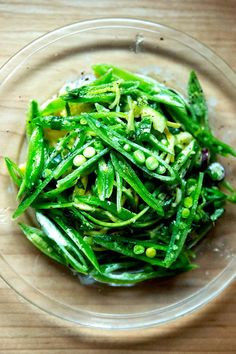 a glass bowl filled with green vegetables on top of a wooden table