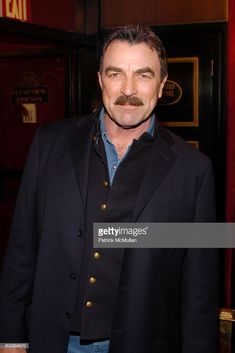 a man with a mustache standing in front of a door