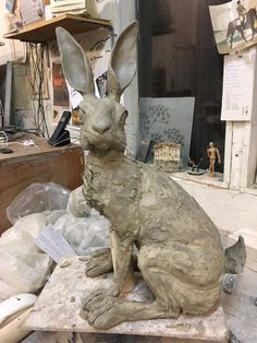 a statue of a rabbit sitting on top of a table next to a pile of papers