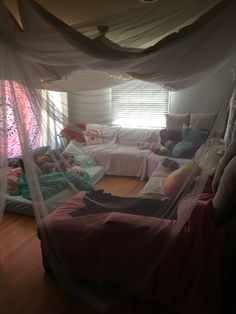 a bed room with two beds covered in mosquito netting and pillows on top of it