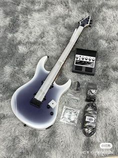 an electric guitar laying on top of a carpet next to other items and accessories,