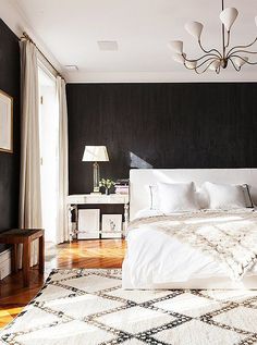 a bed room with a neatly made bed and a chandelier hanging from the ceiling