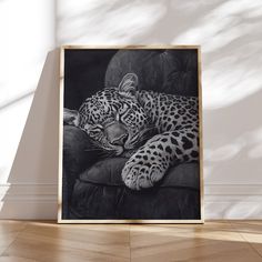 a black and white photo of a leopard laying on a couch with its eyes closed