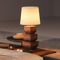 a lamp that is sitting on top of a table in front of a bed with pillows