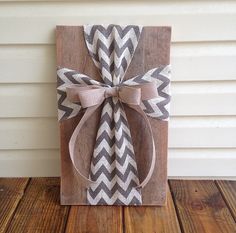 a gift wrapped in brown and white paper with a bow on the front, sitting on top of a wooden box