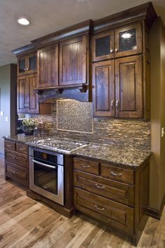 a large kitchen with wooden cabinets and granite counter tops, along with hardwood flooring