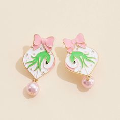 two pink and green earrings with bows on top of each earring, one in the shape of an octopus