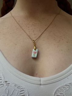 a woman wearing a necklace with a small square shaped object on it's neck