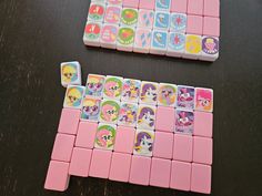 two pieces of pink and white game with cartoon characters on them sitting on a table