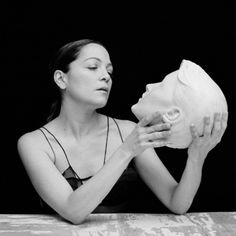 a woman sitting at a table holding a sculpture