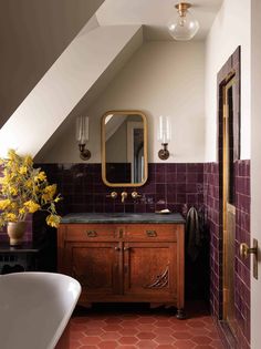 a bath room with a sink a mirror and a bath tub under a slanted ceiling