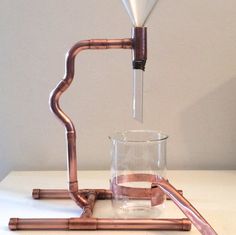 a glass filled with liquid sitting on top of a white table next to a pipe