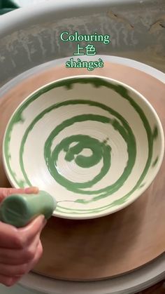 a person is holding a green and white bowl