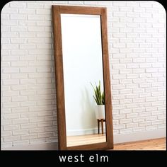 a large mirror sitting on top of a wooden floor next to a plant in a pot