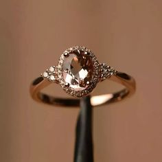 a ring with an oval shaped morganite surrounded by small white and brown diamond accents