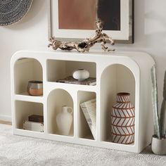 a white shelf with vases and other items on it