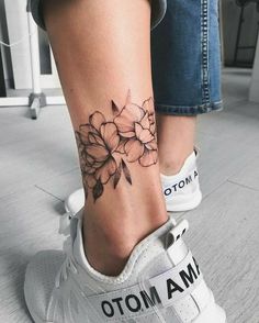 a woman's foot with a flower tattoo on her left ankle and the words i am moto written below it