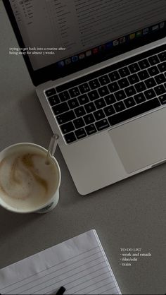 an open laptop computer sitting on top of a desk next to a cup of coffee