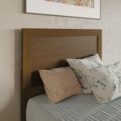 a bed with two pillows on top of it next to a framed painting above the headboard