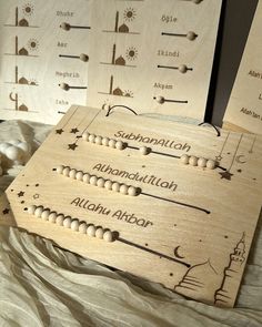 three wooden plaques with names on them sitting on a bed next to balls and beads