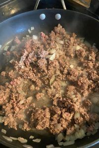 meat and onions cooking in a pan on the stove