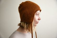 a woman with blonde hair wearing a brown knitted hat and looking off to the side