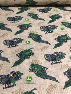 a green and yellow fabric with farm tractors on it's side, in front of an off white background