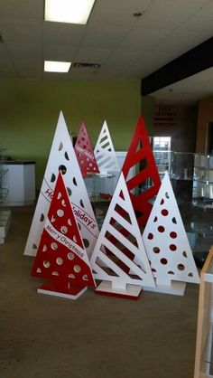 three red and white christmas trees sitting in the middle of a room