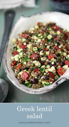 greek lentil salad with tomatoes, cucumbers and herbs in a white bowl