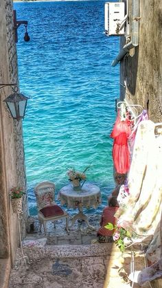 an alley way leading to the ocean with chairs and tables