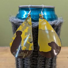 a pair of earrings that are sitting on top of a can with a bear design