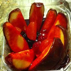 sliced plums in a plastic container with syrup on the top and one half eaten