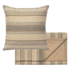 two pillows and a blanket on top of each other, one with a design in the middle