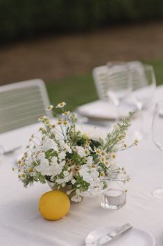 the table is set with white and yellow flowers