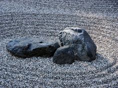 two large rocks sitting on top of a gravel field