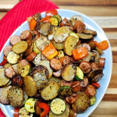 a white plate topped with cooked vegetables on top of a wooden table next to a red towel