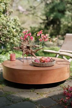 a wooden table with flowers on it and a bowl of fruit sitting on top of it