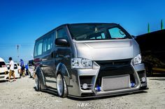 a silver van is parked in front of some other vehicles on the dirt and blue sky