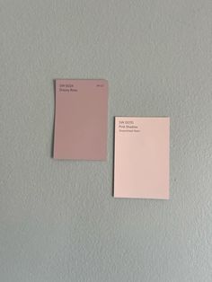 two different shades of pink paint on a white wall and one has a small piece of paper attached to it