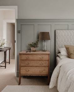 a bed sitting next to a wooden dresser in a bedroom on top of a carpeted floor