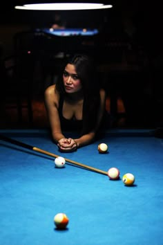 a woman leaning over a pool table with balls in front of her on the floor