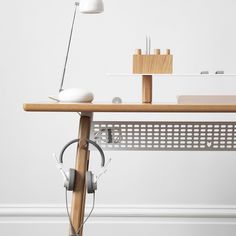 a wooden desk with headphones on it and a lamp next to the table top