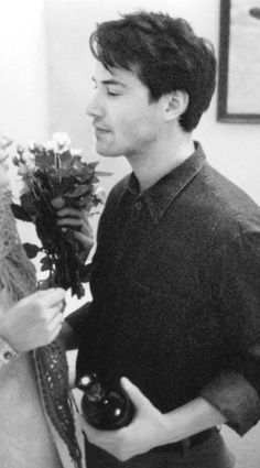 a man and woman standing next to each other in a room with flowers on the wall