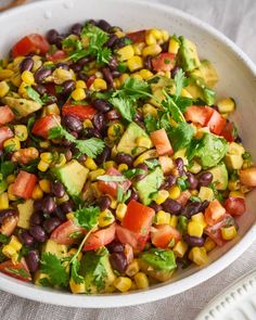 a white bowl filled with black beans, corn and avocado