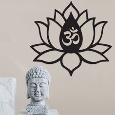 a buddha statue sitting next to a wall with a lotus design on it's face